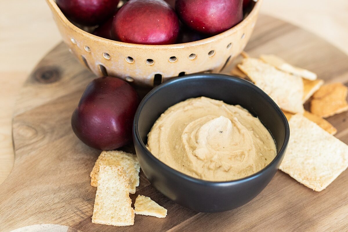 Hummus, pita chips, and plums on summertime table setting in Vista, California.